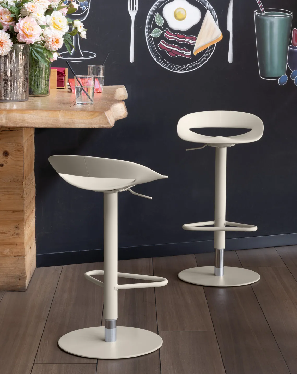 Sgabelli Cosmopolitan Connubia a gas color canapa davanti a una lavagna, accanto a un piano in legno