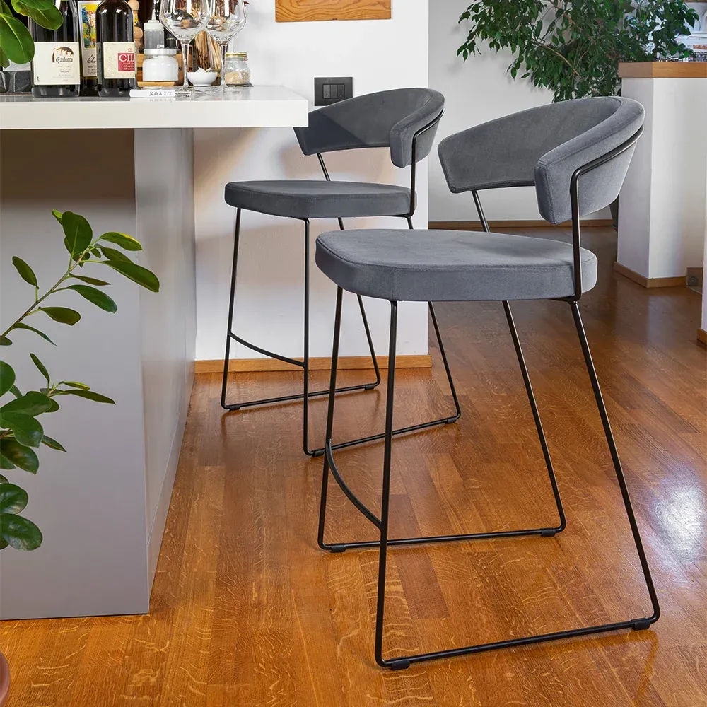 Sgabelli New York Connubia a slitta con rivestimento grigio davanti al piano di una cucina bianca
