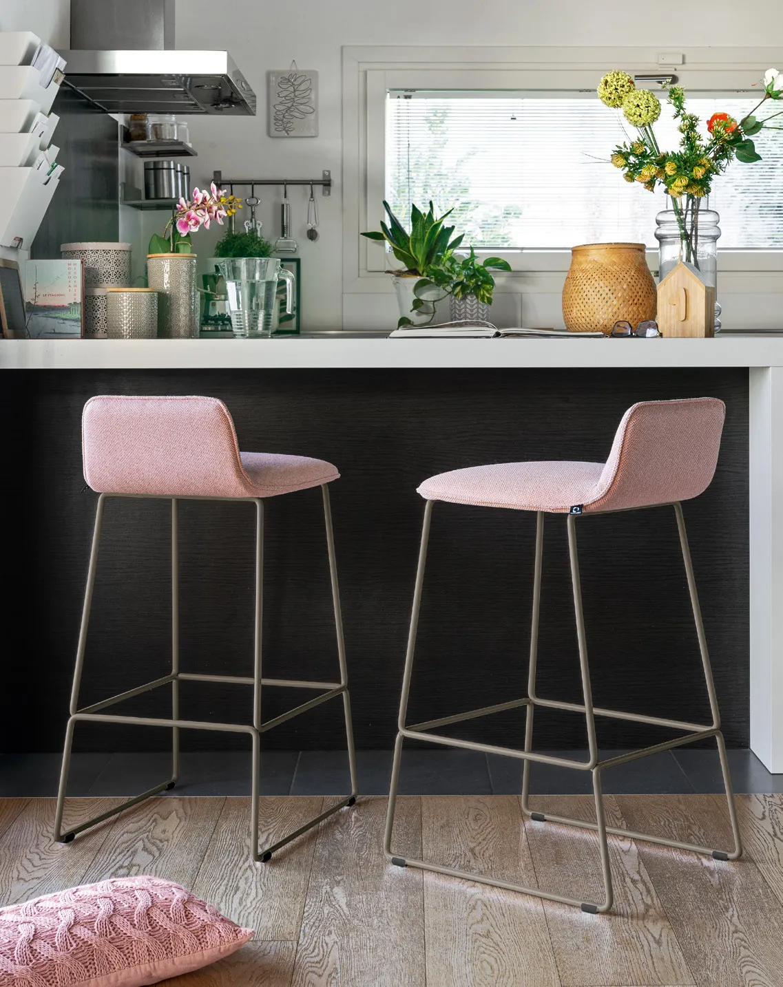 Sgabelli Riley Soft Connubia in tessuto rosa con base a slitta lava, davanti a un'isola da cucina nera