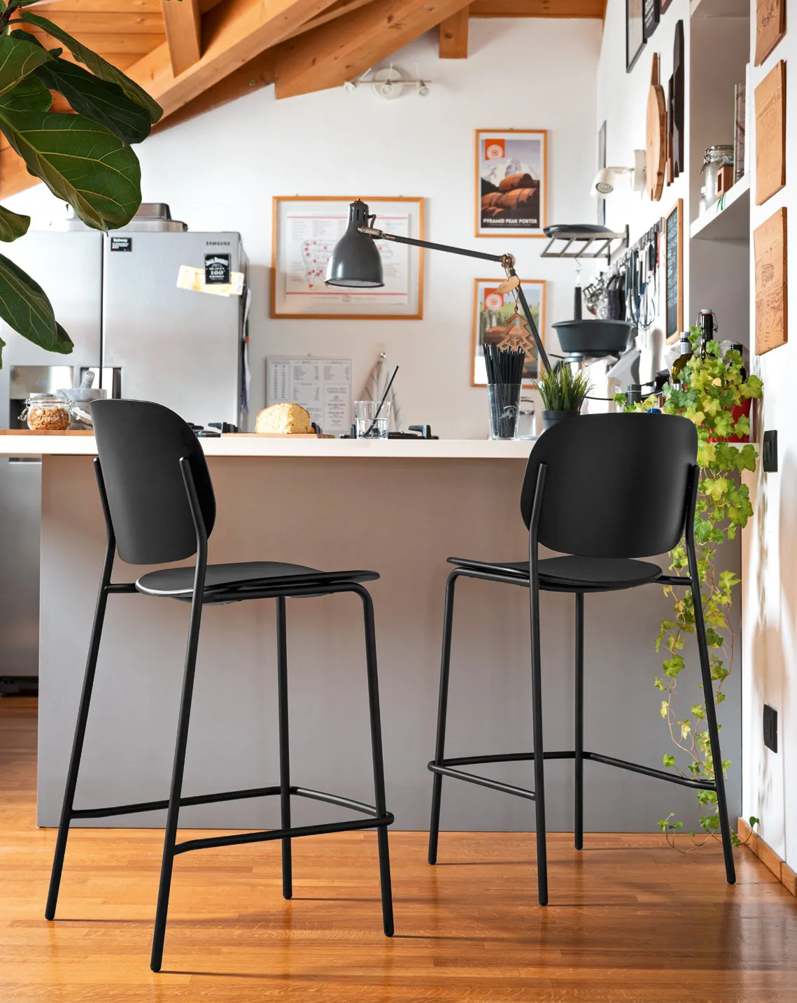 Due sgabelli Yo! Connubia neri davanti a una penisola in una cucina con soffitto in legno