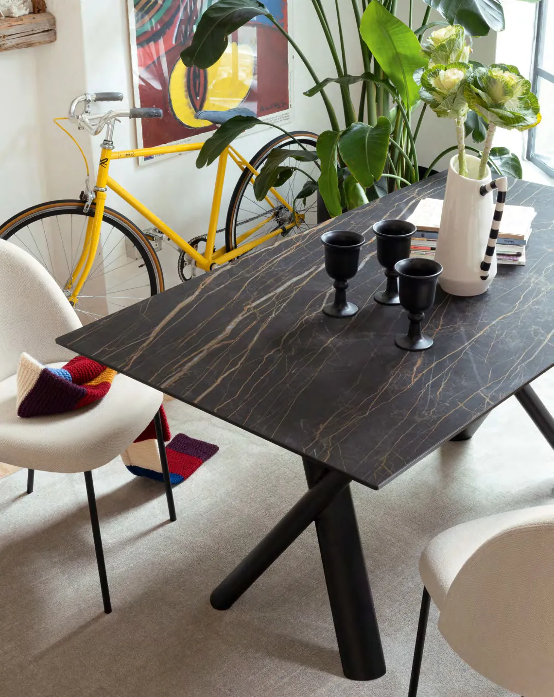 Tavolo Master Connubia nero con piano in ceramica noir désir, sedie chiare e una bicicletta gialla appesa