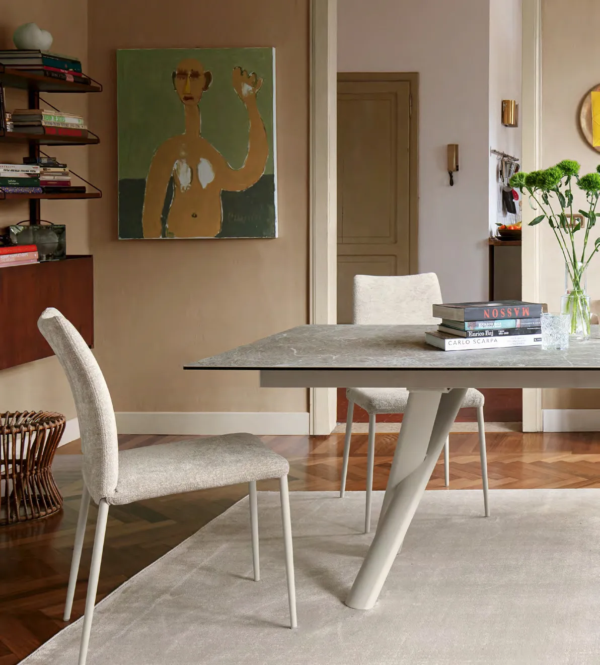 Tavolo Master Connubia canapa con piano arenaria e sedie imbottite chiare in una sala con quadro