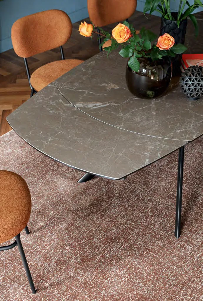 Dettaglio del piano ovale in ceramica del tavolo Giove Plus Connubia con vaso di rose