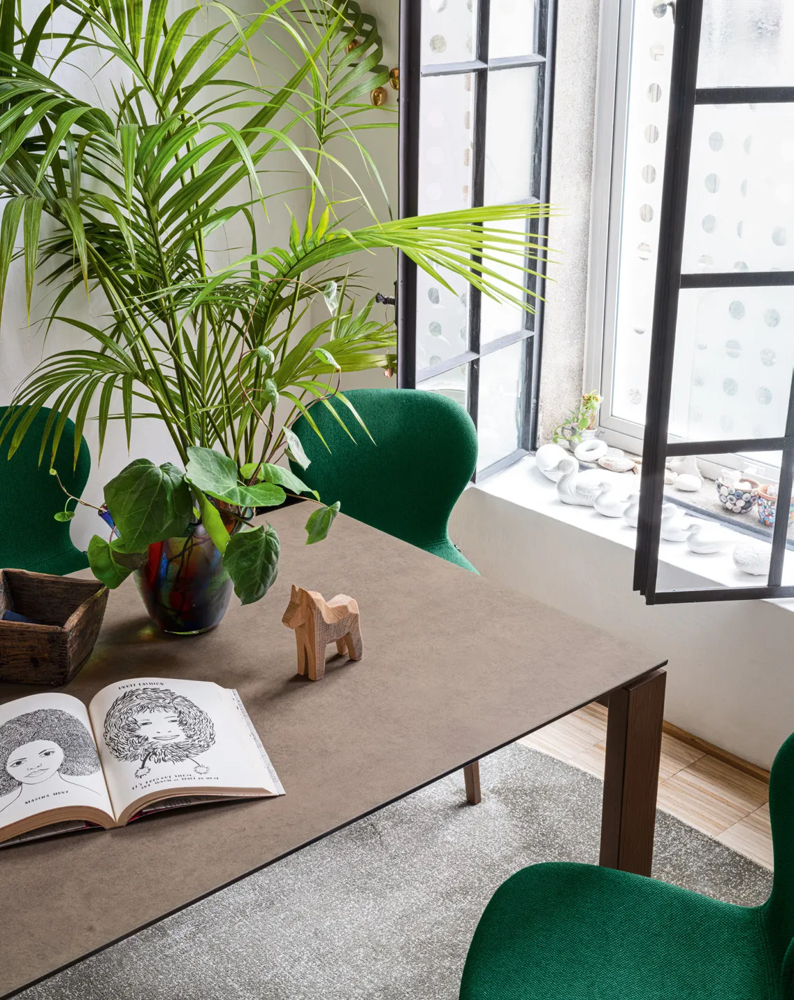 Dettaglio del tavolo Eminence Wood Connubia con libro aperto e cavallino in legno sul piano