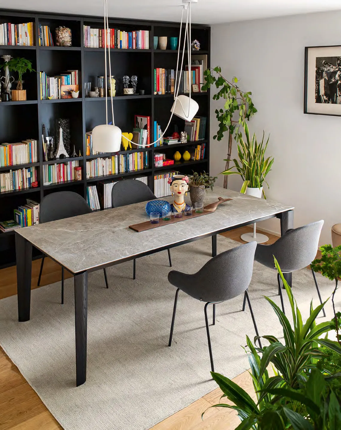 Tavolo Band Connubia in frassino nero con piano in ceramica arenaria davanti a una libreria nera