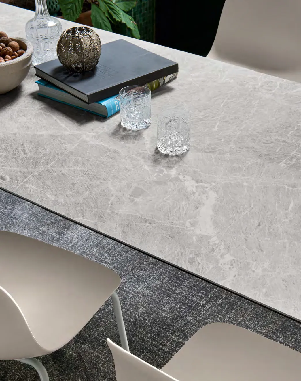 Dettaglio del piano in ceramica arenaria del tavolo Eminence Evo Connubia con libri e bicchieri