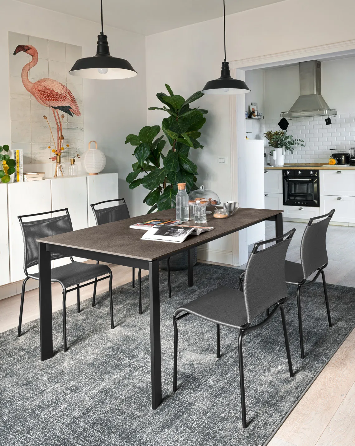 Tavolo Eminence Metal Connubia nero con piano scuro e sedie in rete grigia in una cucina con lampade nere