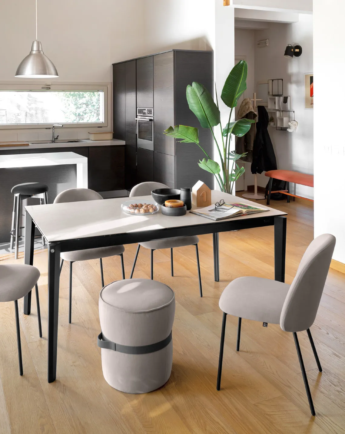 Tavolo Pentagon Fast Connubia nero con piano in ceramica sale e sedie grigie in una cucina con pouf