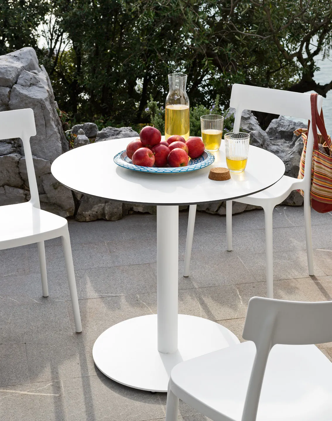 Tavolino Cocktail Connubia bianco con sedie Argo bianche su una terrazza con piante