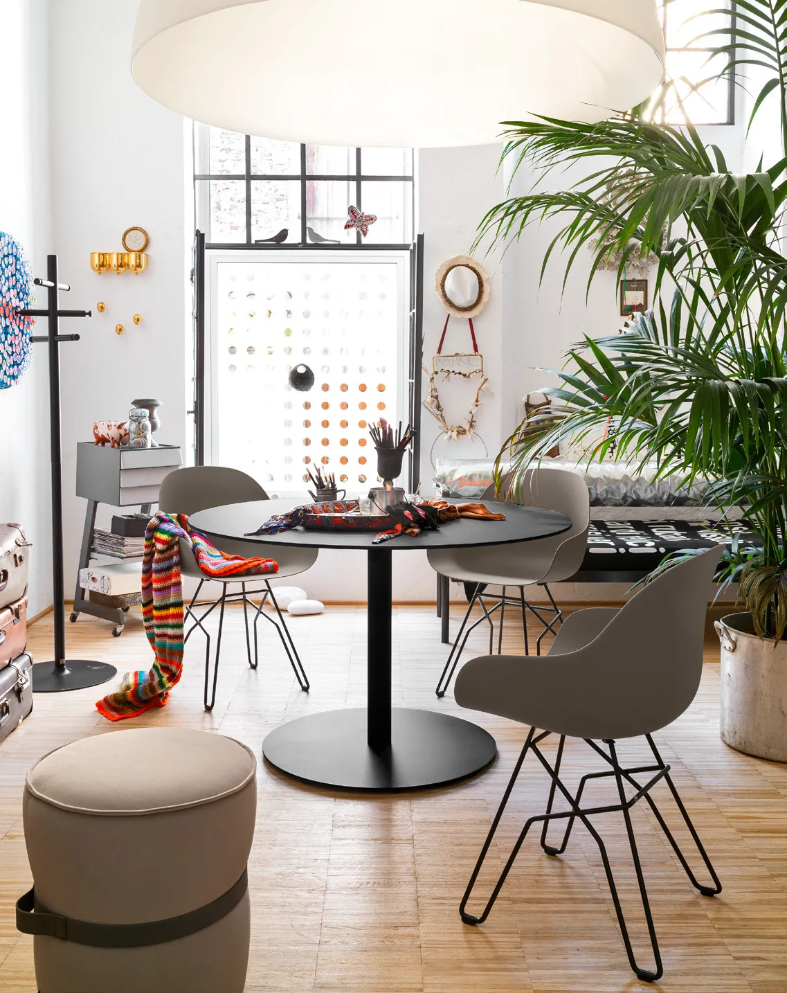 Tavolo Cocktail Connubia nero con sedie Academy in un ambiente con pouf e piante