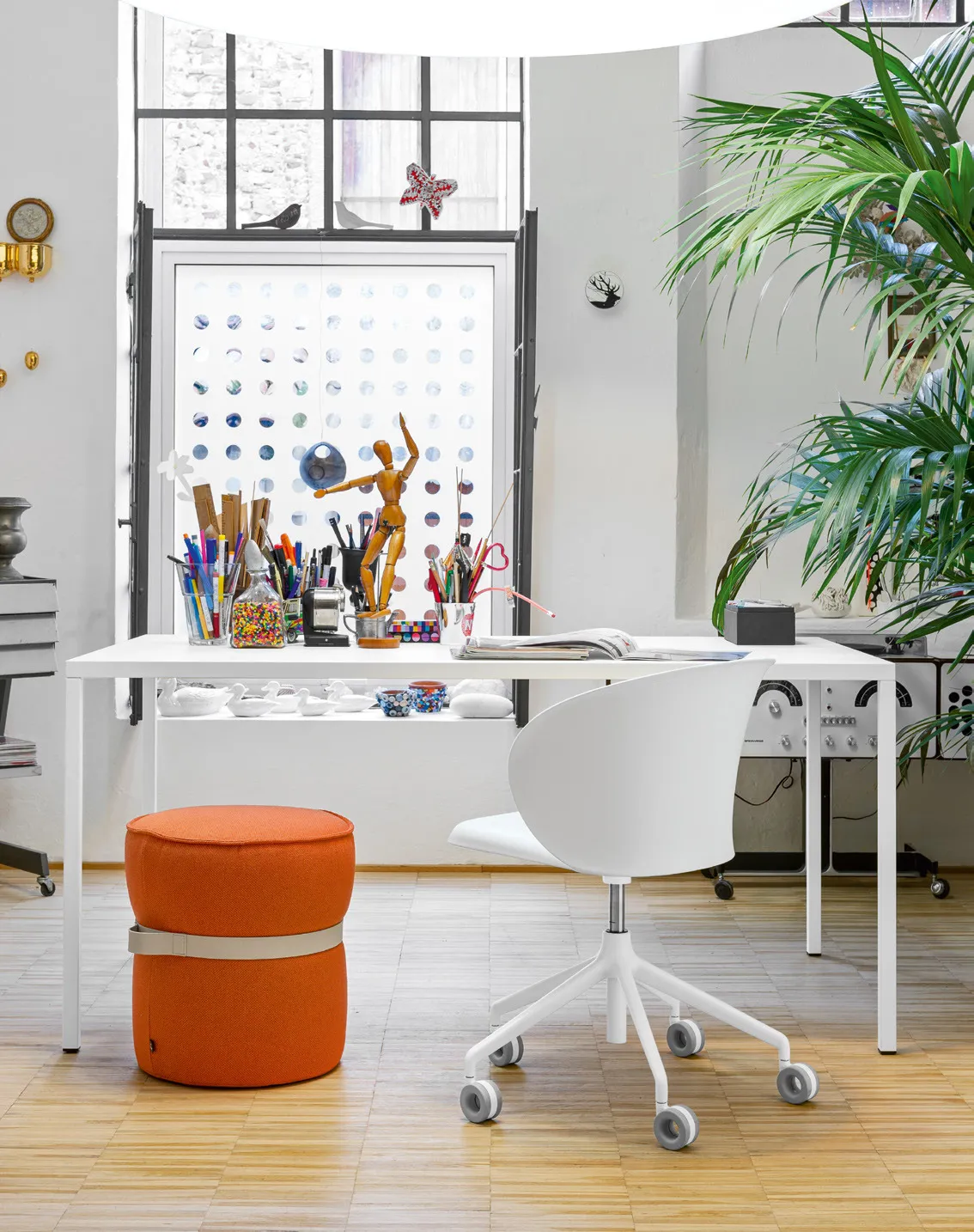 Tavolo Iron Connubia bianco usato come scrivania con sedia girevole bianca e pouf arancio