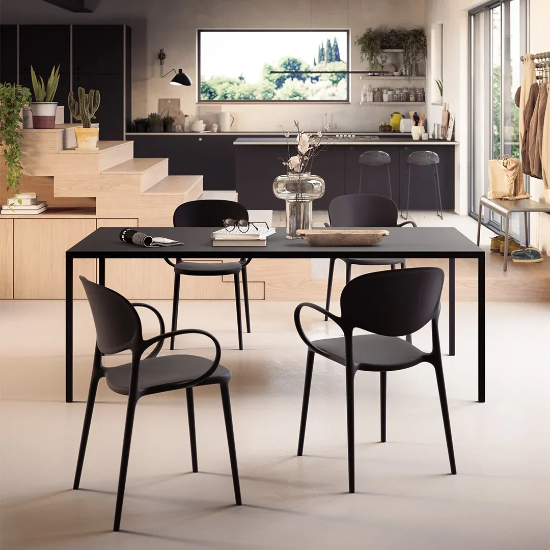 Tavolo Iron Connubia nero con sedie scure in un open space con cucina e gradini in legno
