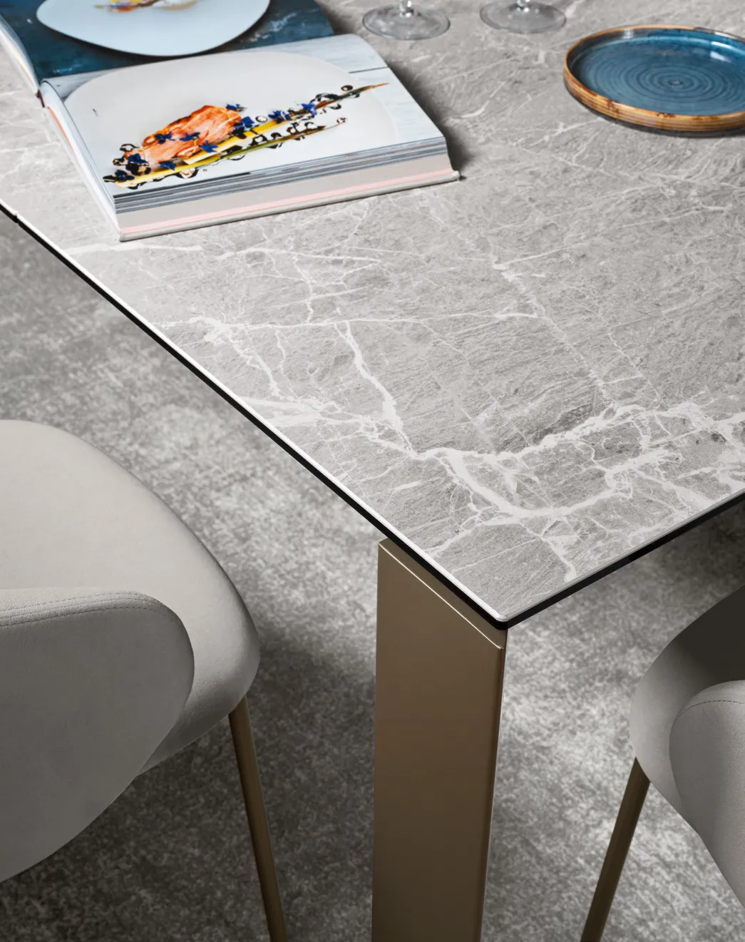 Dettaglio del piano in ceramica grigia venata del tavolo Gate Connubia con un libro