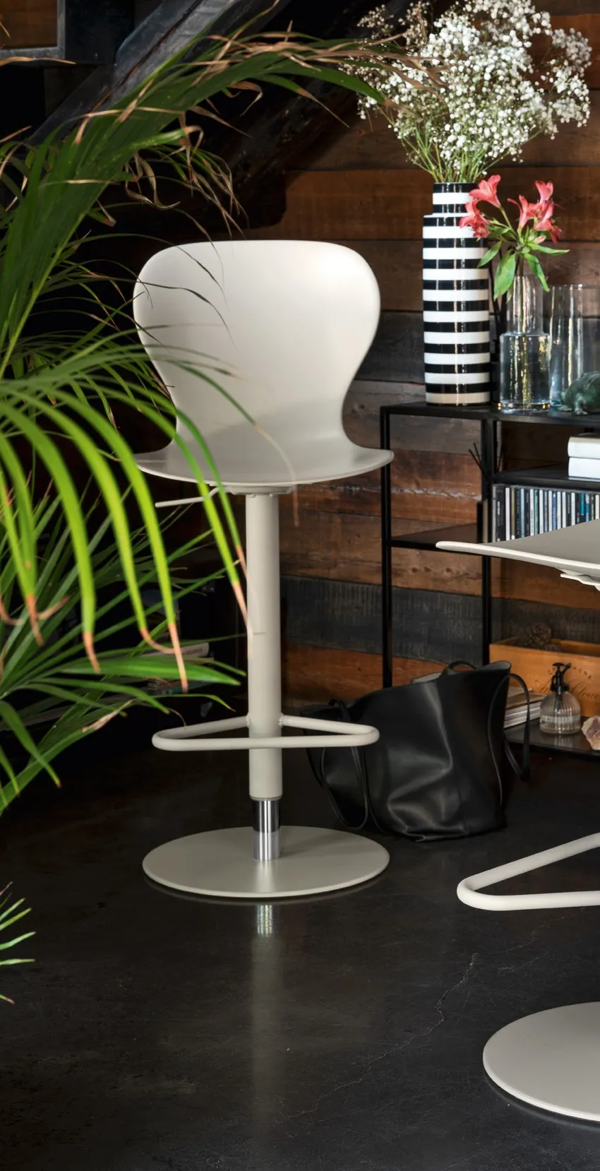 Sgabello Ops! Connubia a gas color canapa davanti a una parete in legno scuro, con un vaso a righe