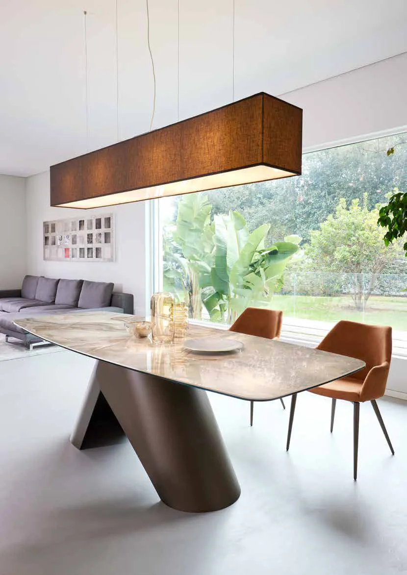 Tavolo Orion Friulsedie con base in ottone e piano Keramic Onice beige sotto una lampada a sospensione