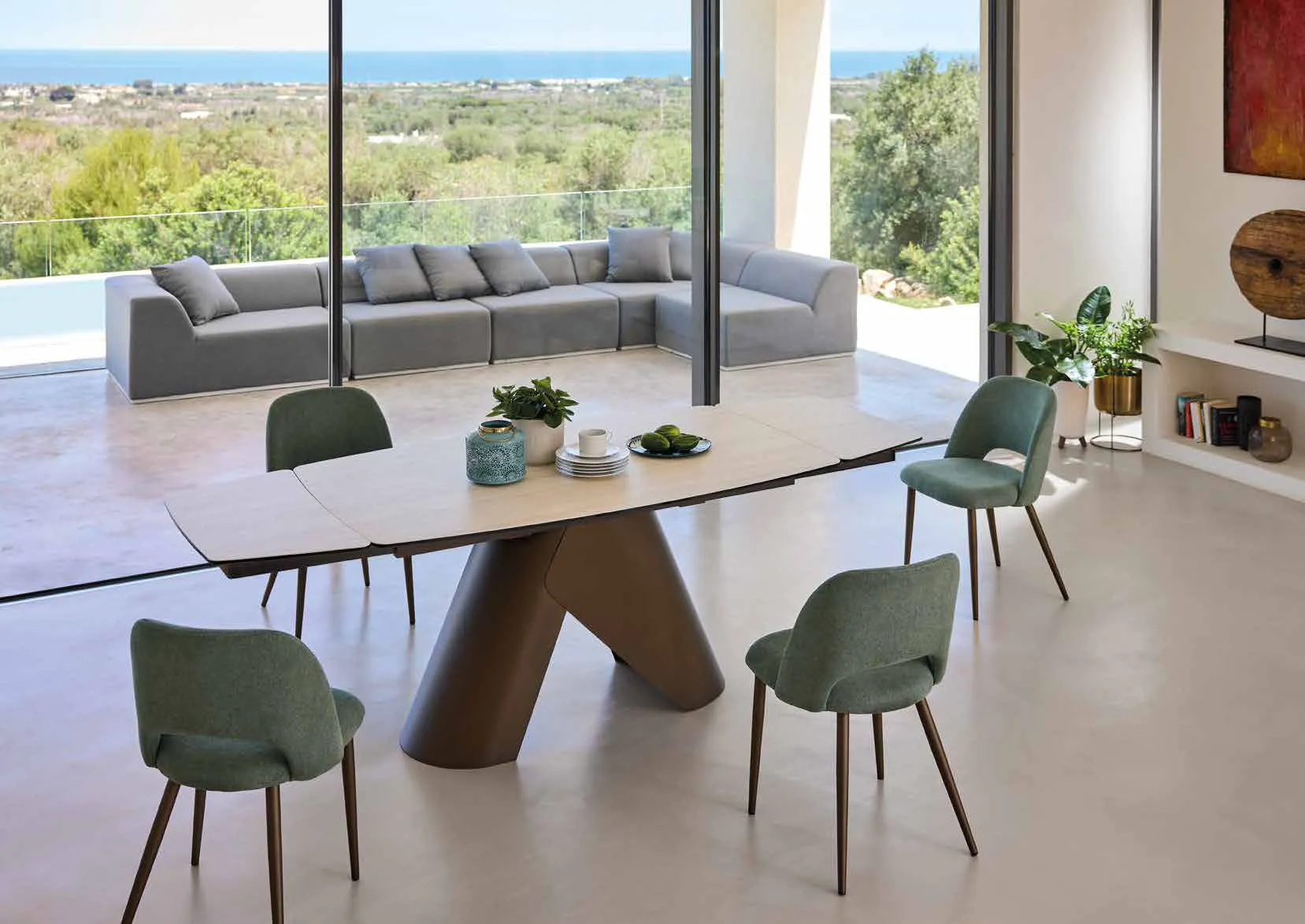 Tavolo Orion Medium Friulsedie con piano Travertino bianco e sedie verdi in un living con vista