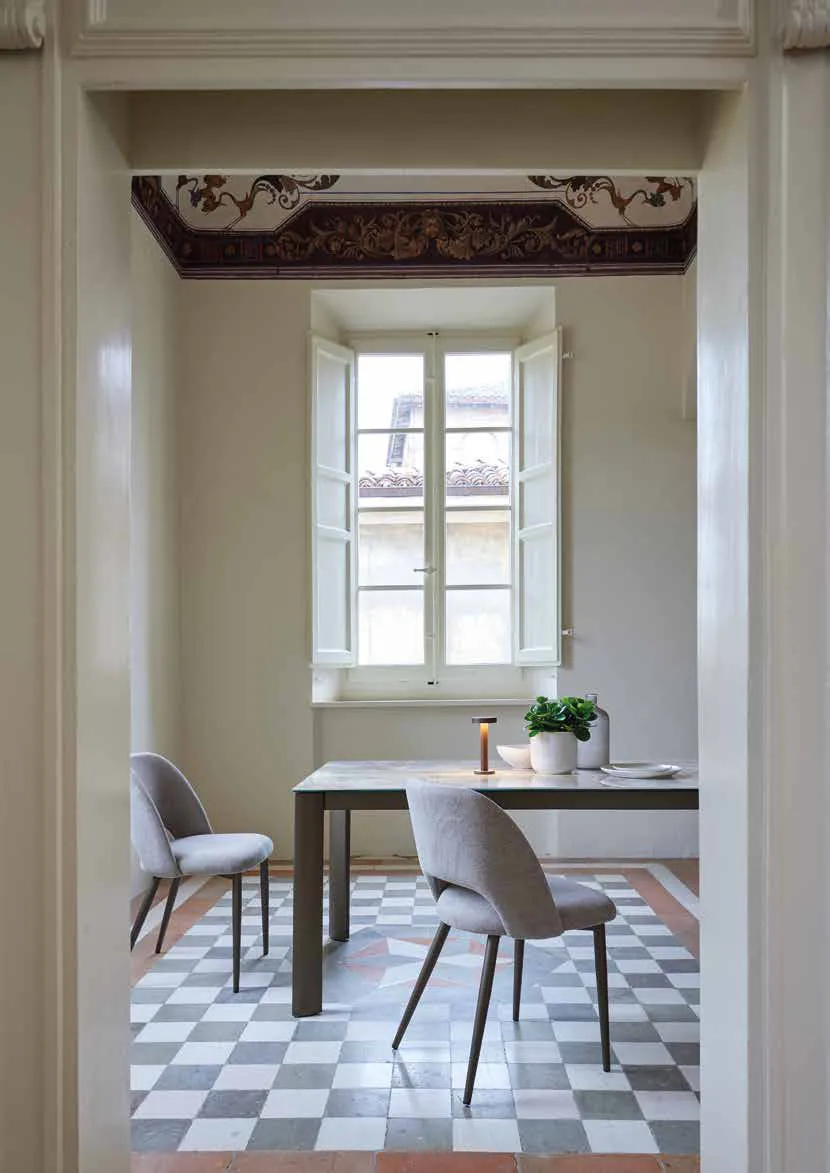 Tavolo Zeno Friulsedie in ottone con piano Keramic Onice beige e sedie Beverly, visto da una porta