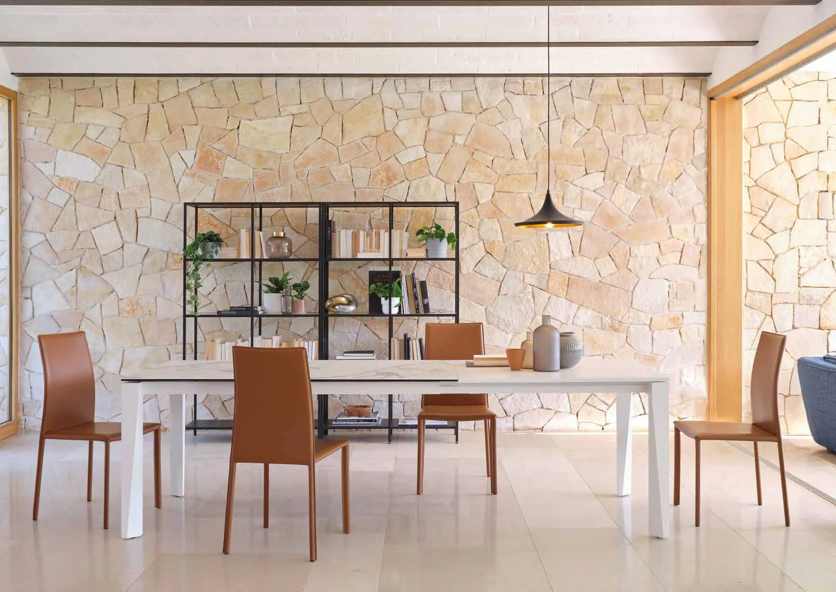 Tavolo allungabile Matrix Friulsedie laccato bianco con sedie Vanity cognac davanti a un muro in pietra