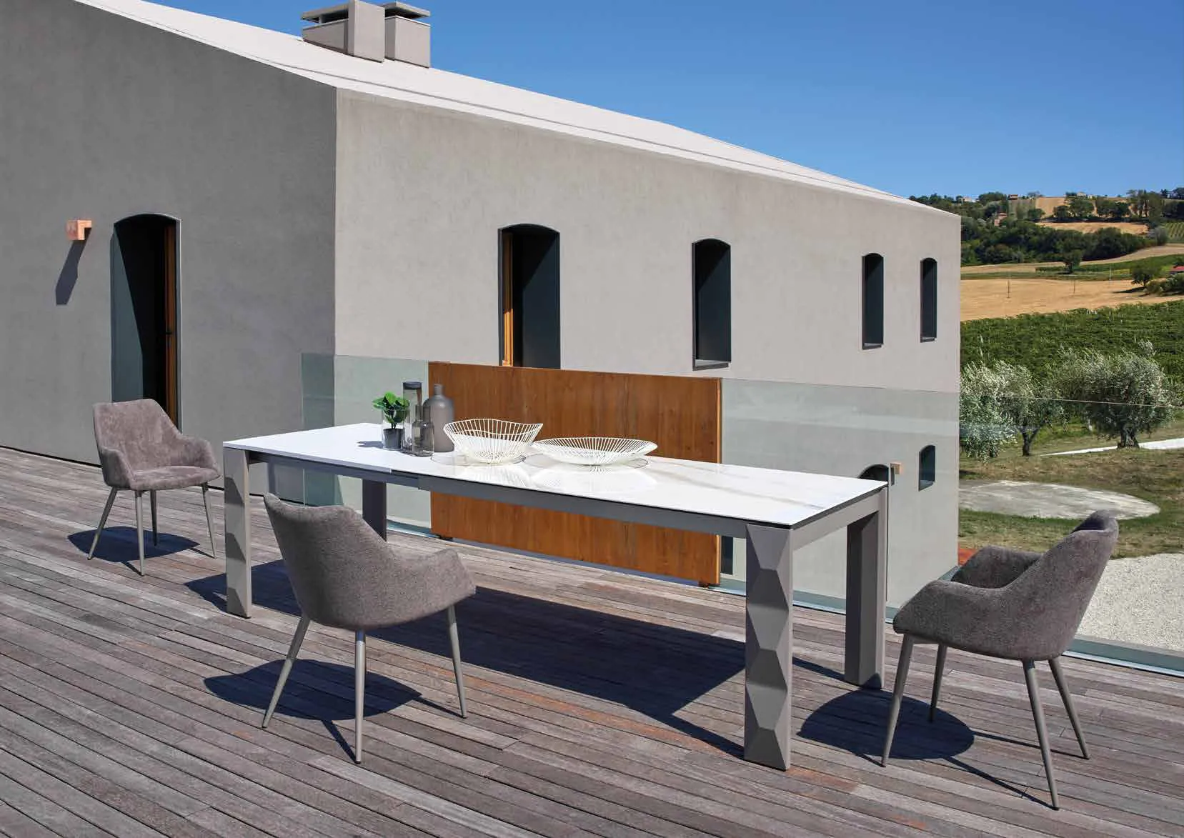 Tavolo Diamond Friulsedie titanio con piano Keramic Calacatta e poltroncine Janis su una terrazza