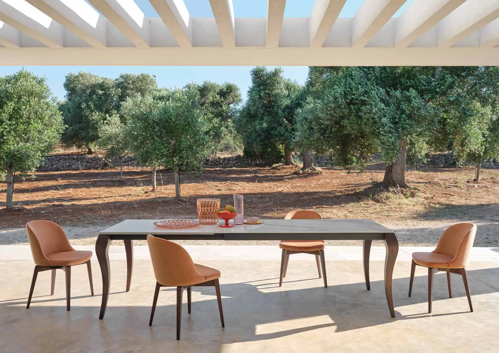 Tavolo Victor Friulsedie in frassino bruciato con sedie cognac sotto una pergola fra gli ulivi