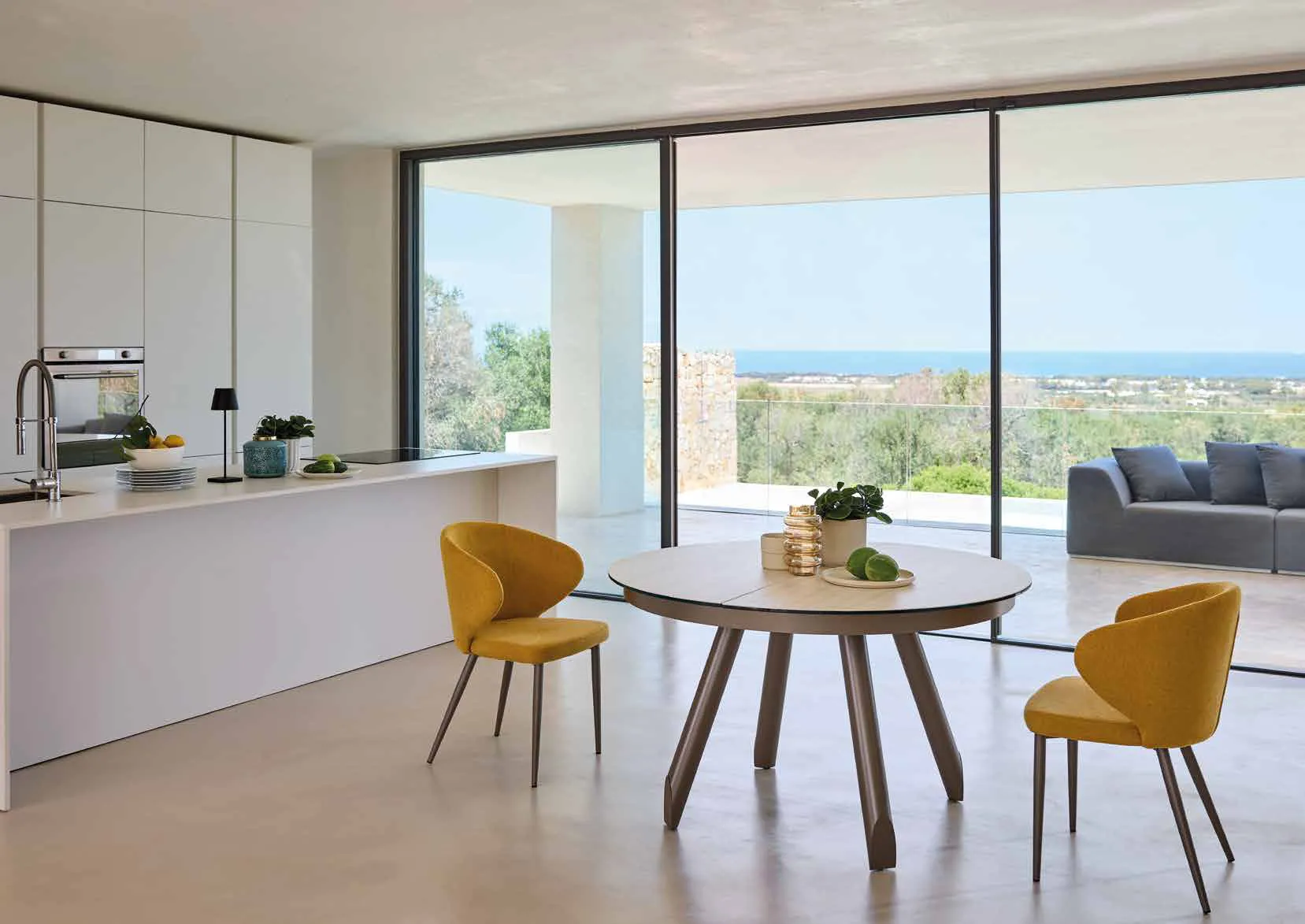 Tavolo rotondo allungabile Newton Friulsedie in ottone con piano Keramic Travertino e poltroncine gialle