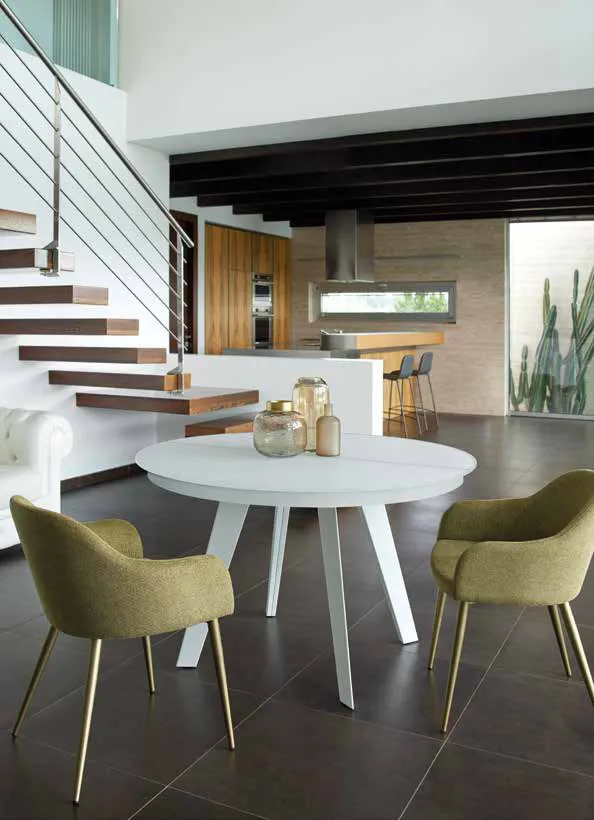 Tavolo Sirius Friulsedie bianco con piano in vetro tondo in un living con scala