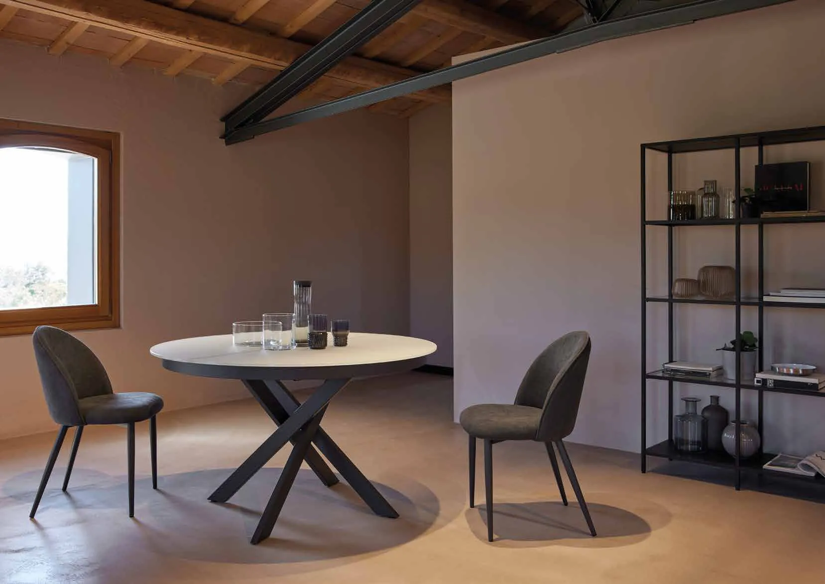 Tavolo Apollo Friulsedie antracite con piano in vetro bianco tondo e sedie Bally in un soggiorno