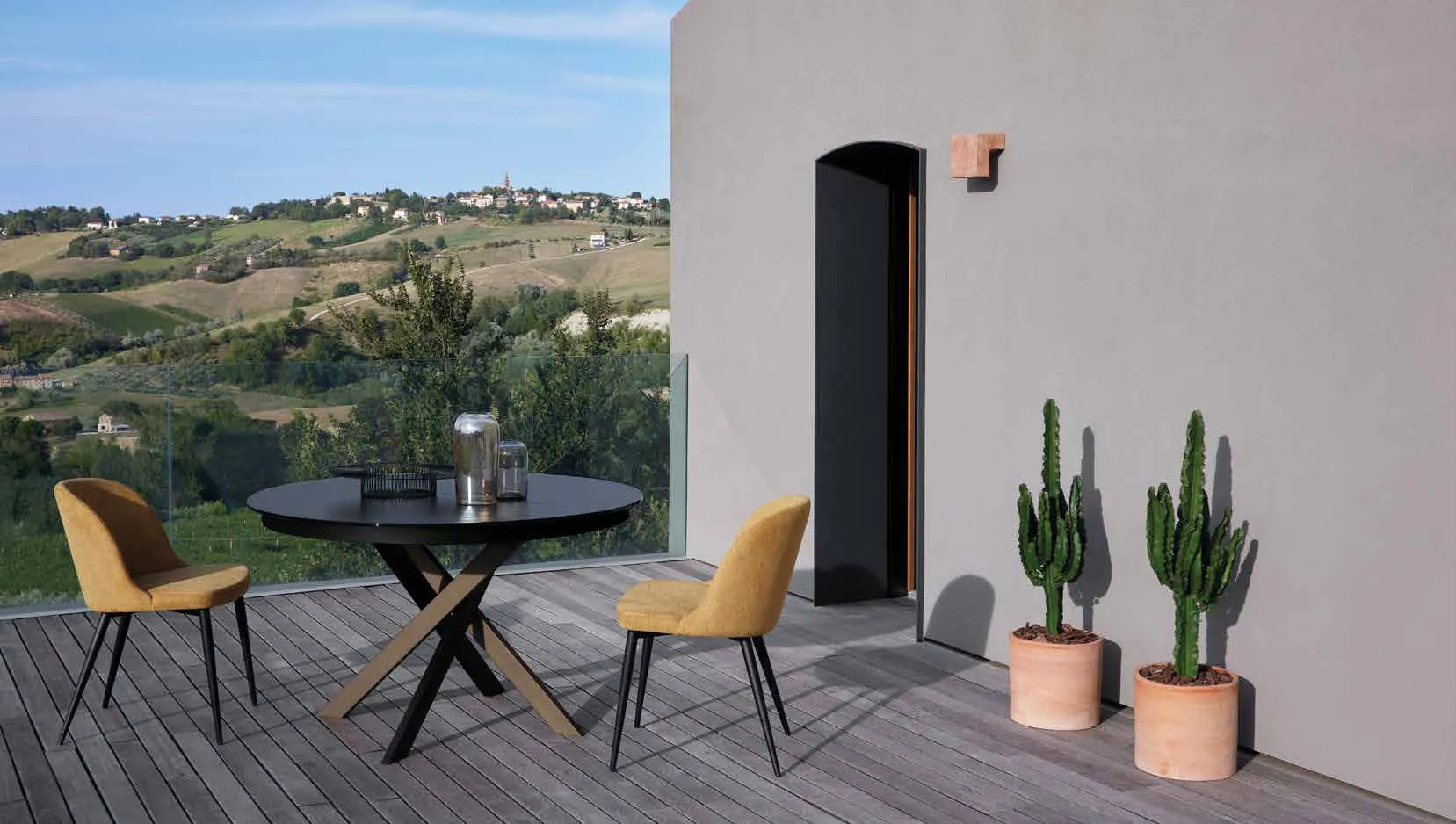 Tavolo Apollo Friulsedie bicolore con piano in vetro nero e sedie Cleo gialle in terrazza