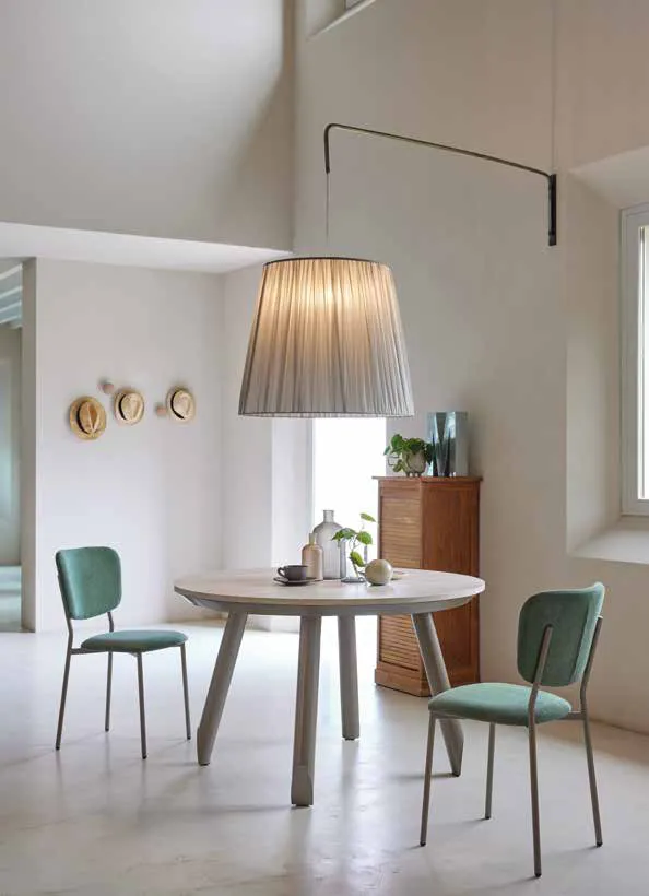 Tavolo Tolomeo Friulsedie in titanio con piano Tivoli travertino in una sala con lampada
