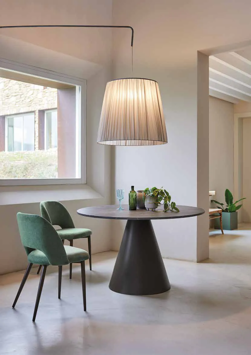 Tavolo Globe Friulsedie antracite con piano tondo Caspio Dark e sedie verdi sotto una lampada