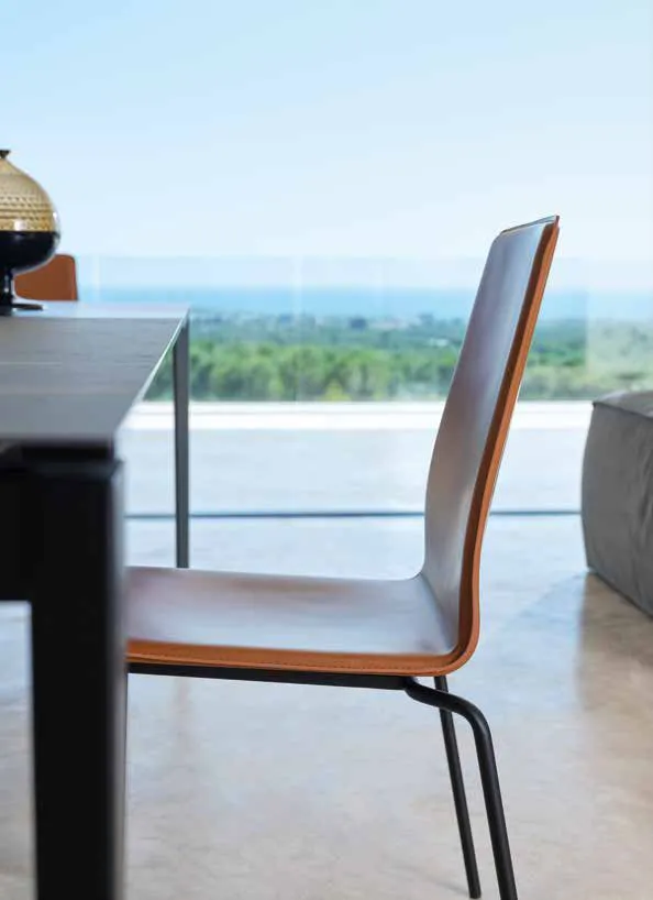 Sedia Gran Manon Friulsedie cognac accanto al tavolo con vista sul paesaggio