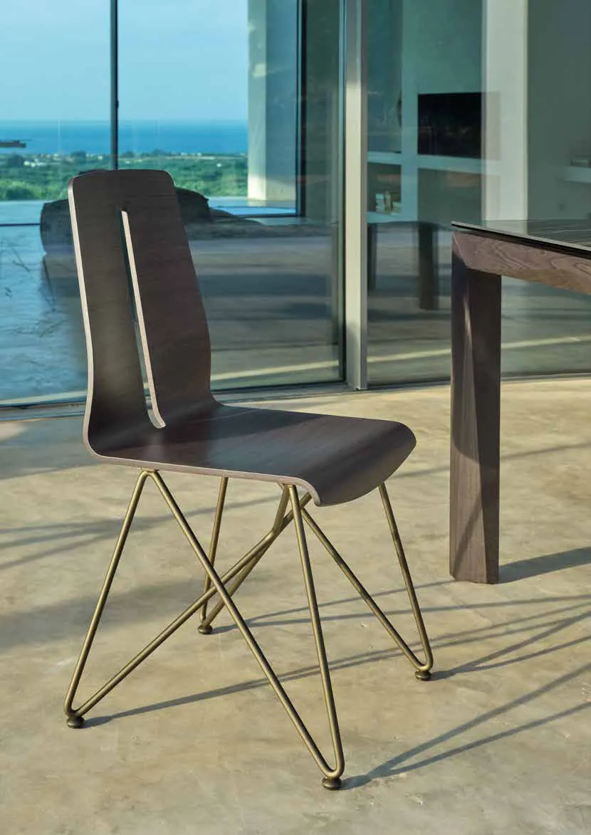 Sedia Greta Friulsedie in rovere bruciato con base in tondino ottone accanto al tavolo