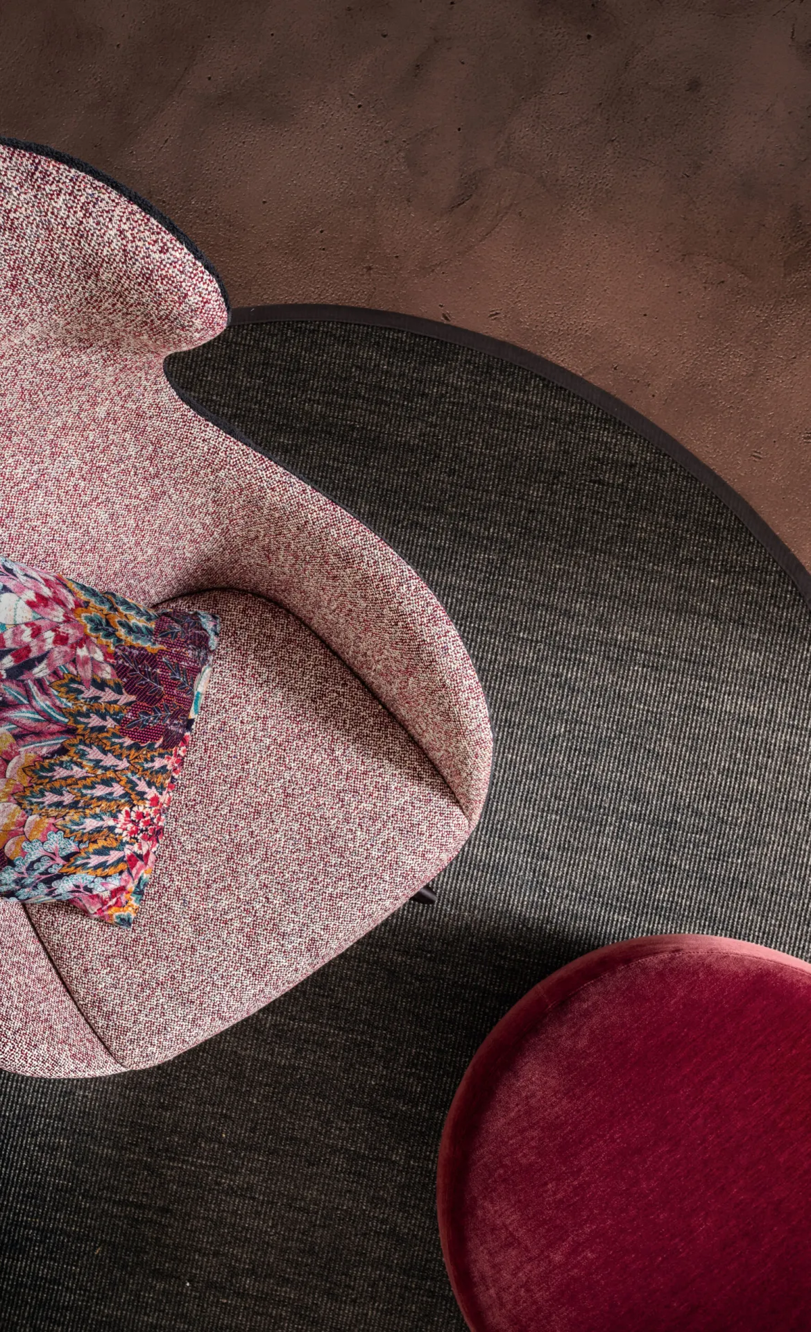 Poltrona Ginger Samoa rosa vista dall'alto accanto a un pouf rosso