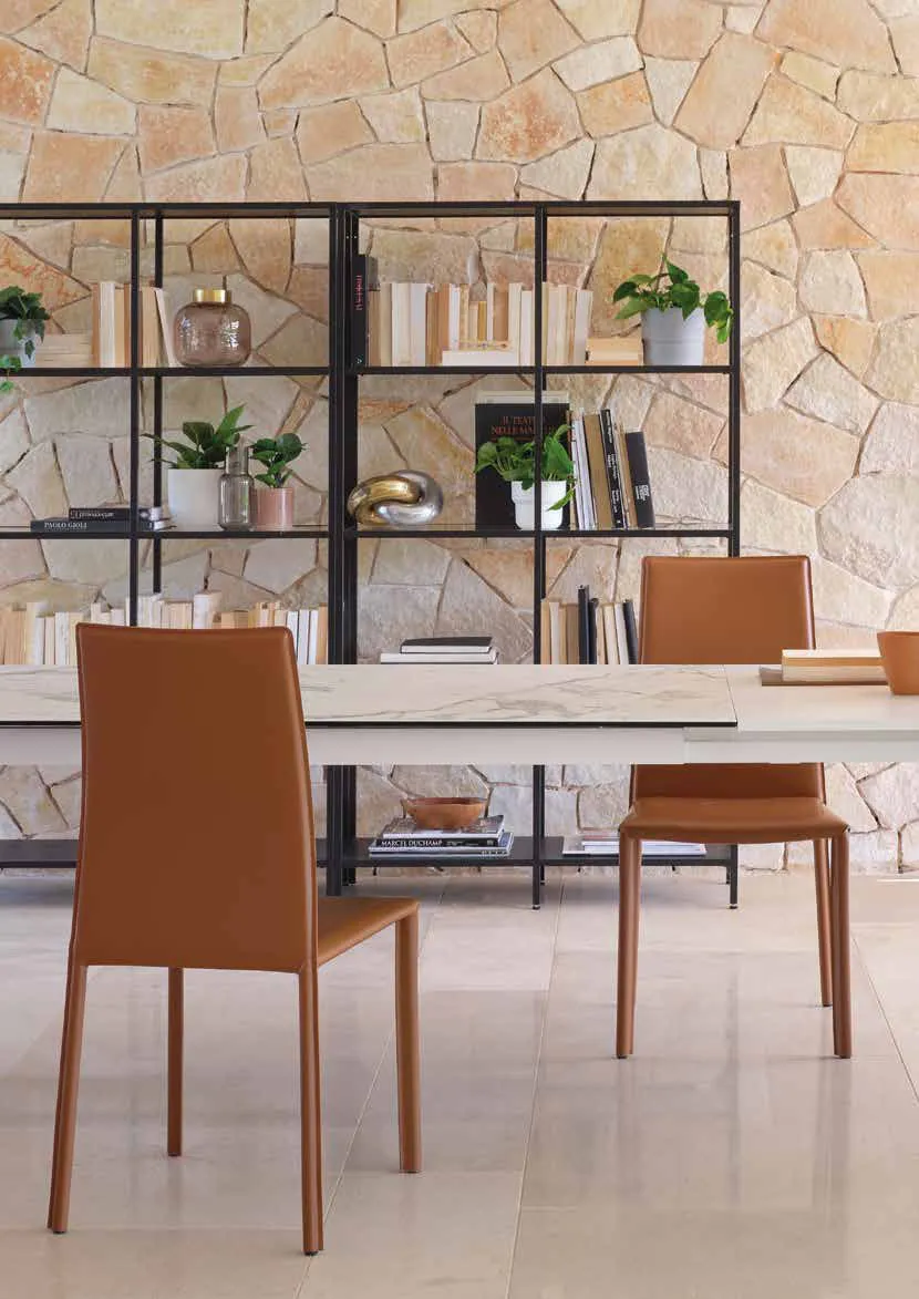Sedie Vanity Friulsedie in cuoio rigenerato cognac davanti a una libreria
