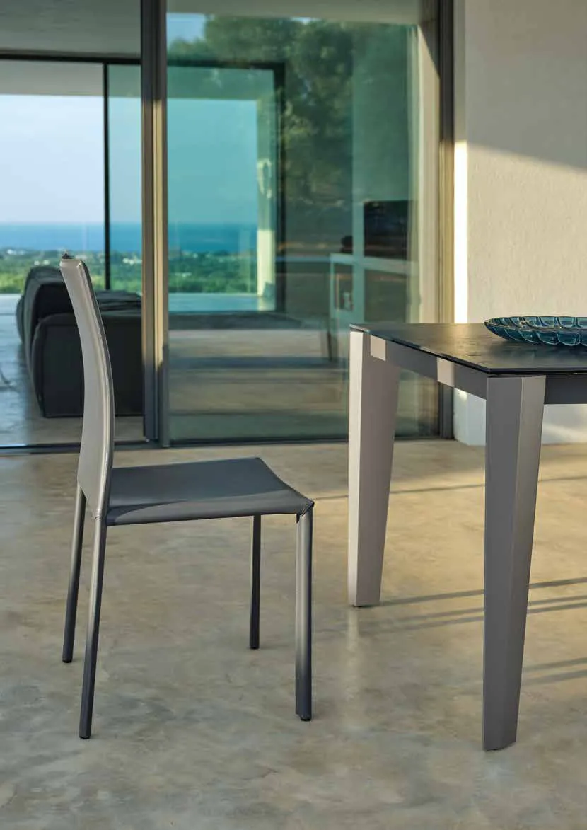 Sedia Vanity Friulsedie in cuoio rigenerato antracite accanto al tavolo Spencer