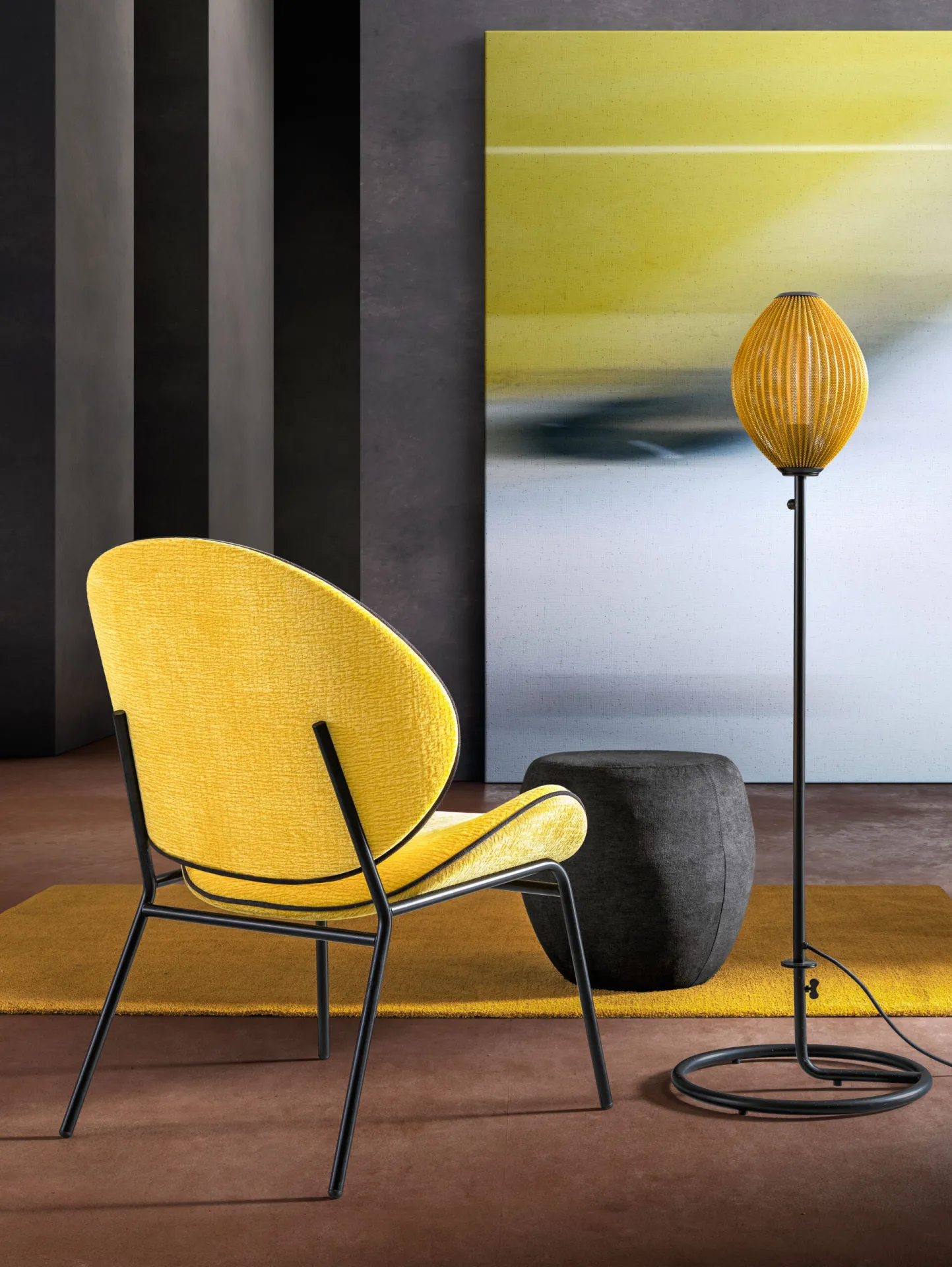 Poltroncina Pinko Samoa gialla su tappeto senape, accanto a un pouf grigio e a una lampada