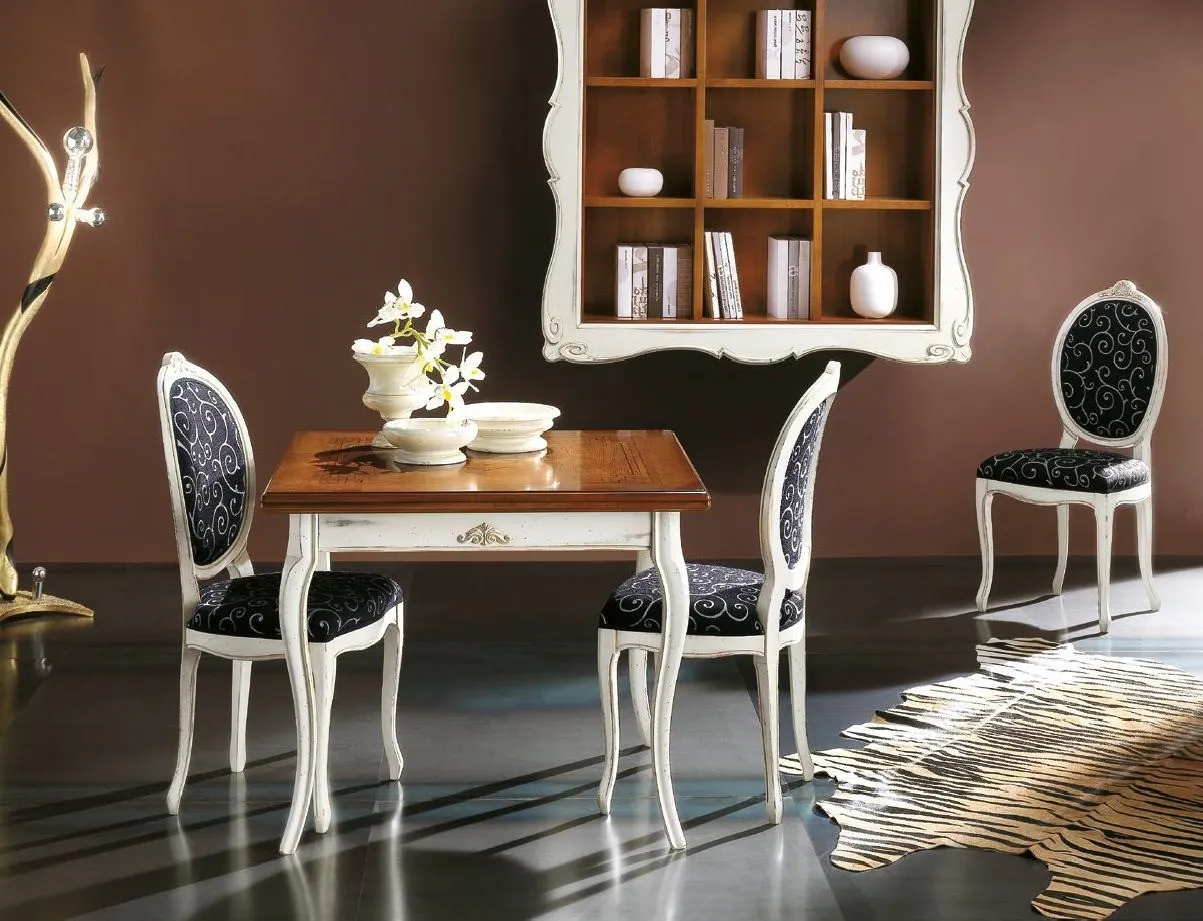 Tavolo Trend Style Imba con piano intarsiato e sedie bianche davanti a una libreria a cornice