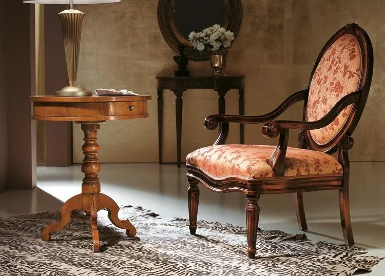 Poltroncina Trend Style Imba con schienale ovale in tessuto a fiori accanto a un tavolino intarsiato