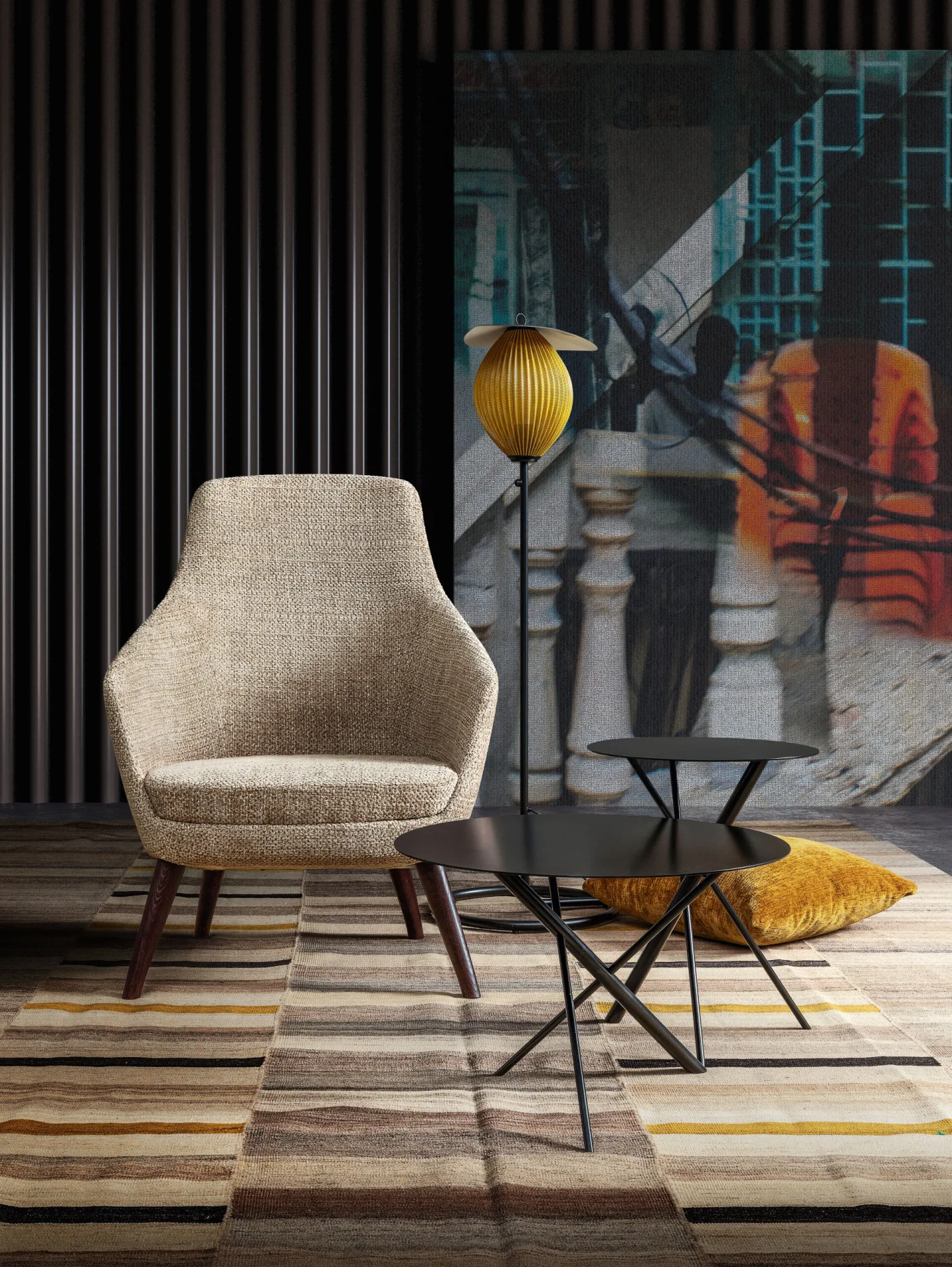 Poltrona Kora Samoa beige su gambe in legno scuro, accanto a un tavolino nero e a una lampada