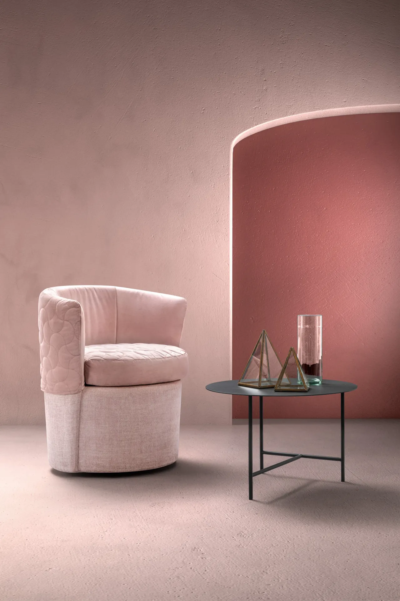 Poltroncina Peggy Samoa rosa con base chiara e interno trapuntato, accanto a un tavolino