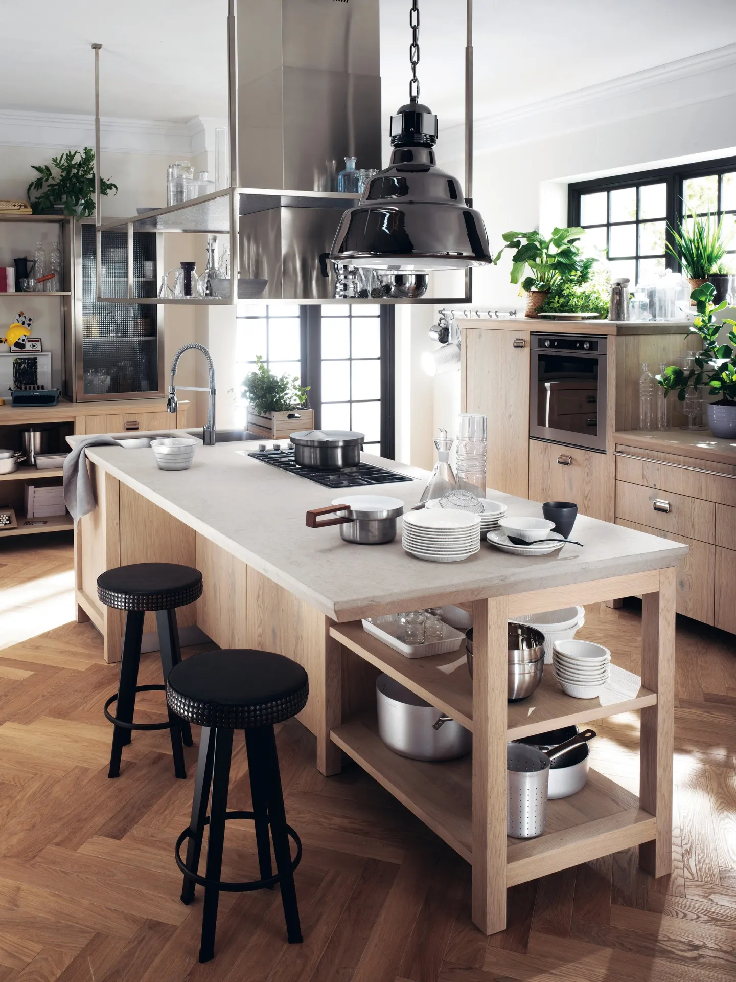 Sgabelli Barstud Scavolini neri davanti a un'isola in legno chiaro in una cucina industriale