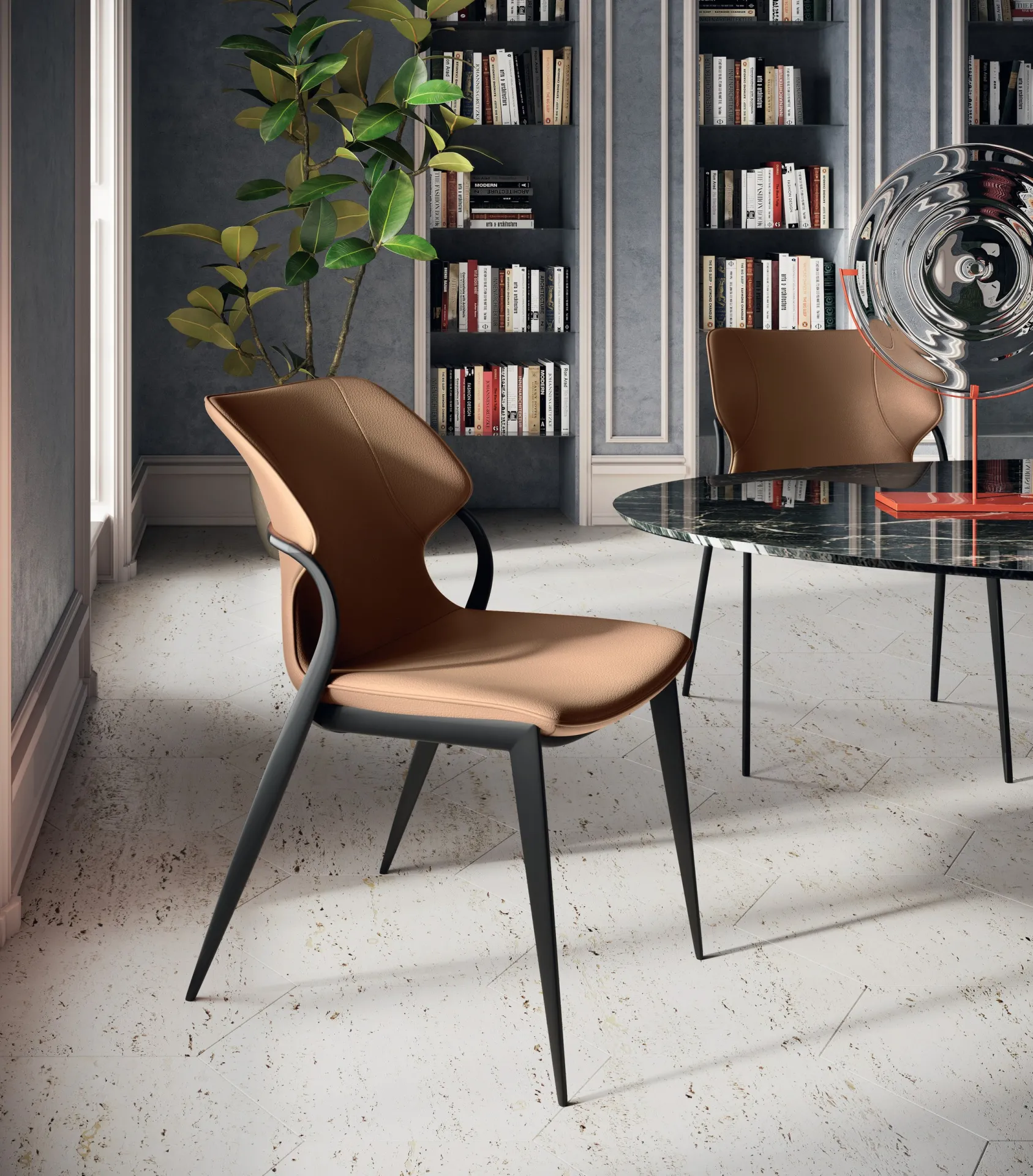 Sedie Batlò Scavolini color cuoio intorno a un tavolo tondo in marmo, con librerie sullo sfondo