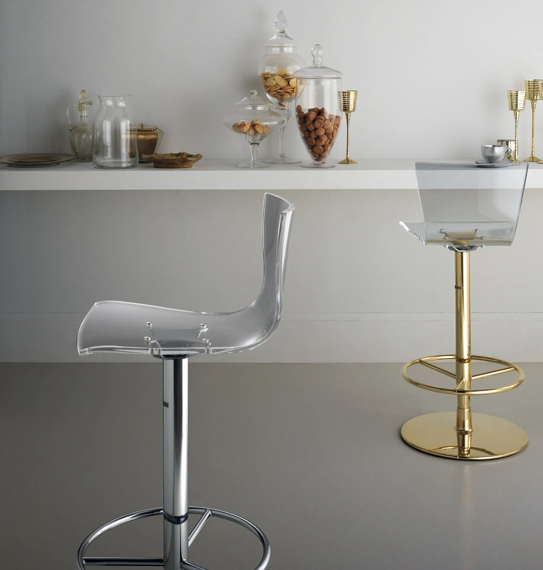Sgabelli Deluxe Scavolini cromato e ottonato davanti a una mensola con barattoli di vetro