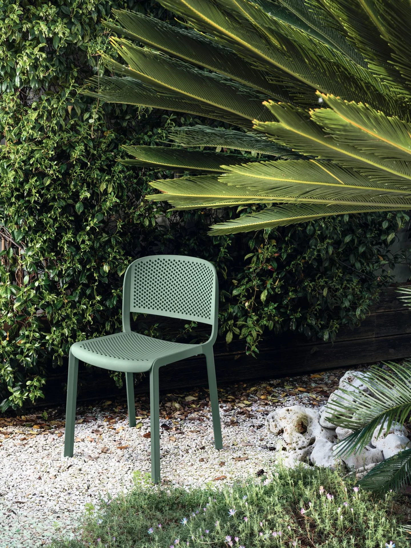 Sedia Dome 261 Scavolini verde salvia in un giardino tra palme e ghiaia