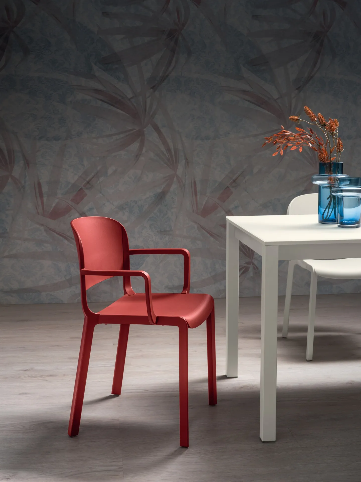 Sedia Dome 265 Scavolini rosso corallo con braccioli accanto a un tavolo bianco