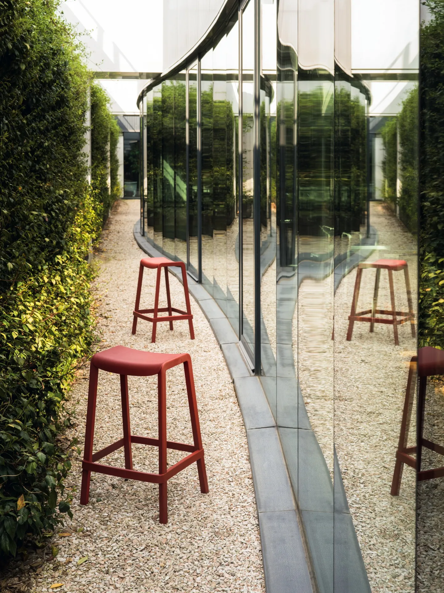 Sgabelli Dome 267 Scavolini rossi in un giardino accanto a una parete a specchio