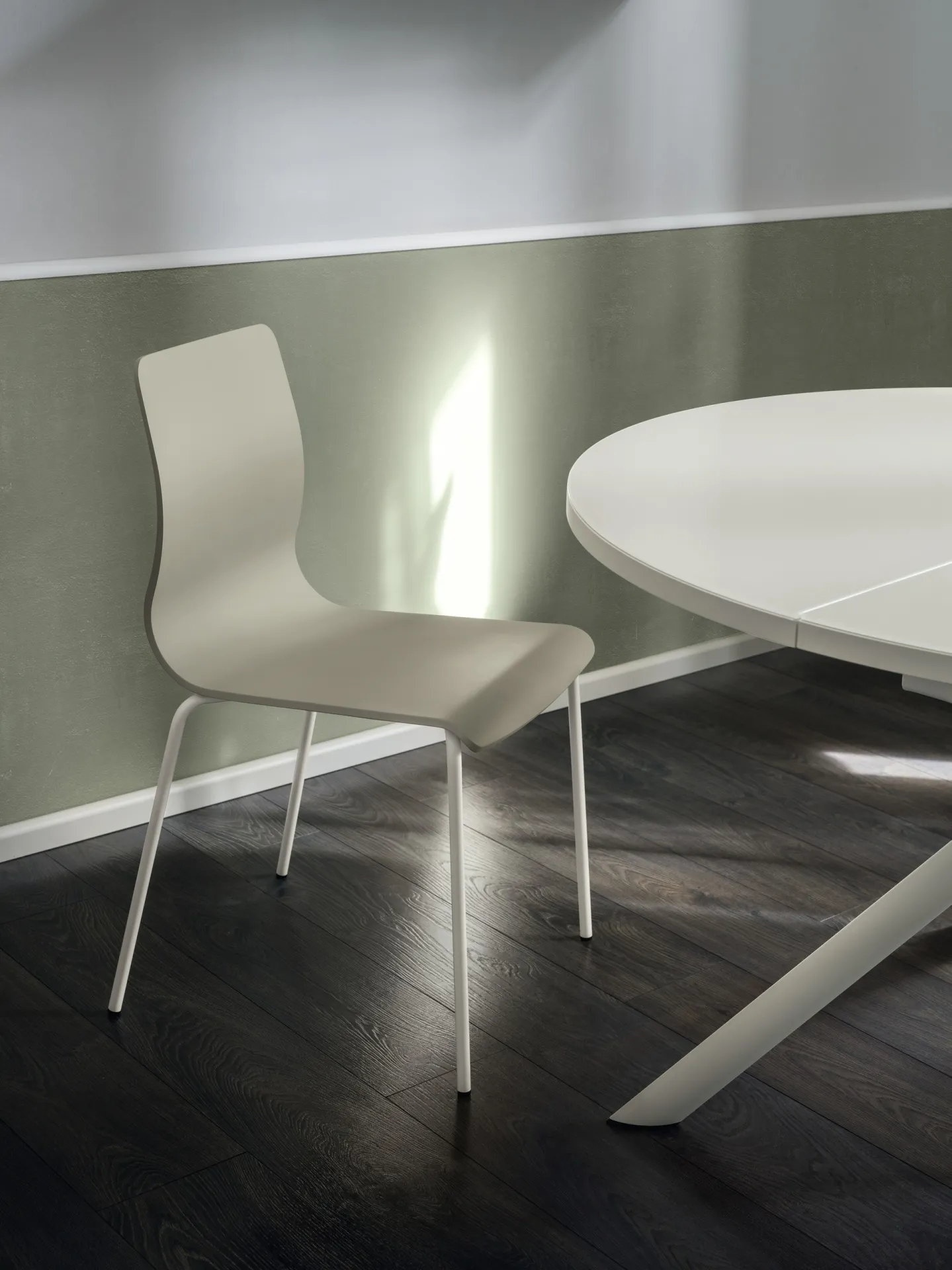 Sedia Endless Scavolini color crema accanto a un tavolo tondo bianco