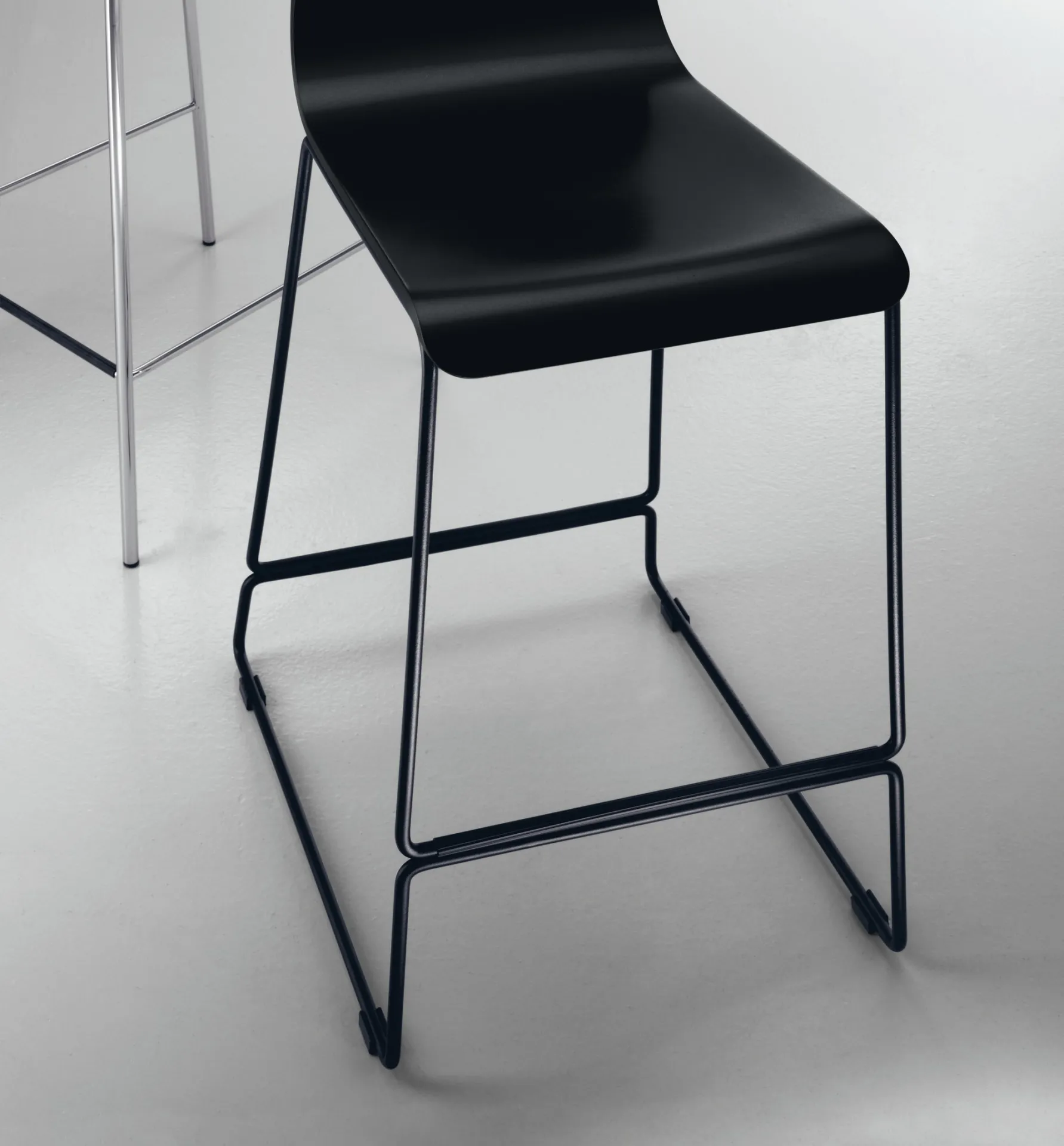 Sgabello Endless a slitta Scavolini nero in primo piano in un ambiente chiaro