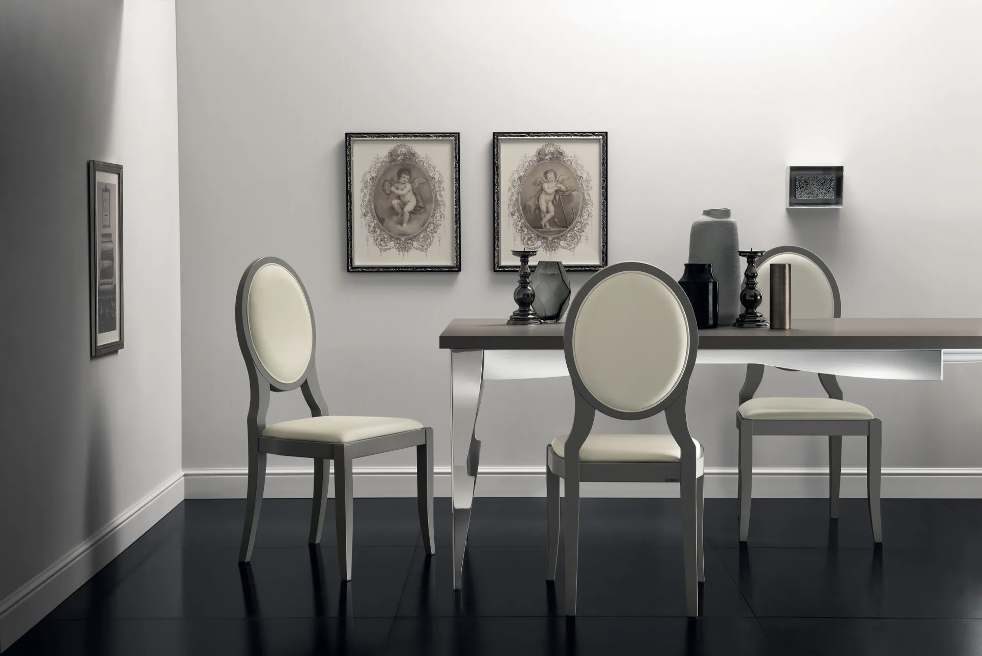 Sedie Exclusiva Scavolini laccate chiare attorno a un tavolo, con stampe incorniciate alle pareti