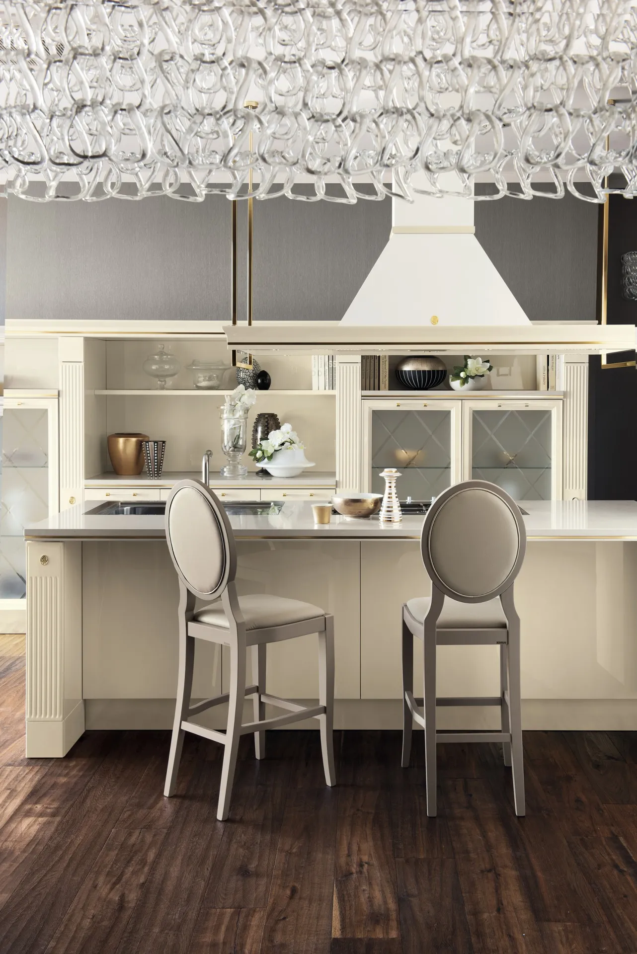 Sgabelli Exclusiva Scavolini intorno all'isola di una cucina classica sotto un lampadario di cristallo
